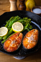 roasted salmon fillet steak with broccolini and lemon slice on iron skillet pan