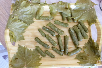 Process of making stuffed grape leaves with olive oil, selective focus. It is called "Yaprak Sarma", or "Dolma", "Salamura Yaprak" in Turkish. It is prepared with ground beef, rice and tomato paste.