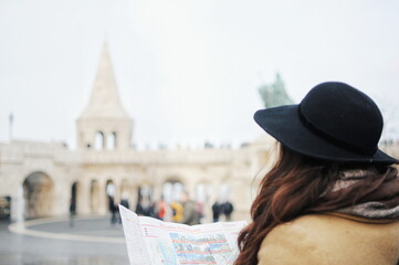 Woman travel alone abroad in winter time. Girl look at the map to see city.