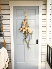 door of the house decorated for fall with dried corn