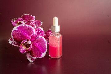 Fototapeta na wymiar Bottle of rose essential oil, bath salt and phalaenopsis on vinous background