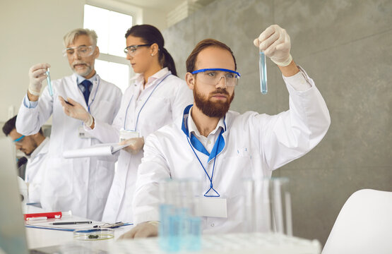 Pharmaceutical or chemical industry research and experimentation. Male scientist or chemist carefully and thoughtfully examines the liquid in a test tube. Man works with chemicals in a science lab.