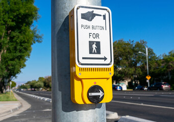 Pedestrian crosswalk call button installed at traffic lights with a dedicated pedestrian signal. Urban street background