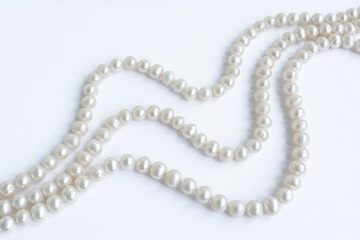 Abstract arranged three rows of natural pale pearl necklace on white paper background