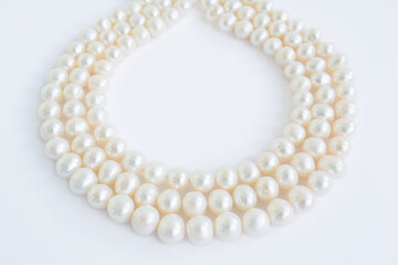 Three rows of pale natural pearl necklace on white background