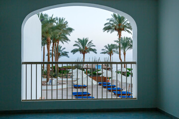 Palm trees and sun loungers throughout the hotel view from the balcony.