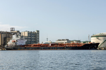 cargo ship on the river bank next to industrial facilities