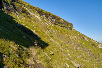 Woman hiker with backpack on a trail in the mountains