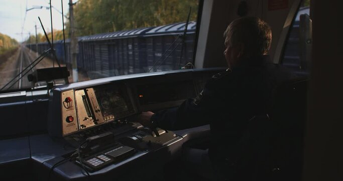 Train Conductor. A train driver, a professional driver of a train or a car of a ground and underground metro in the cab of an electric train. The train goes through the forest, autumn landscape