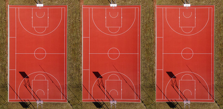 Drone view of three basketball court from above. Outdoor field activity from top view. Birds eye. White lines and green grass. Aerial image from drone. People gathering places.