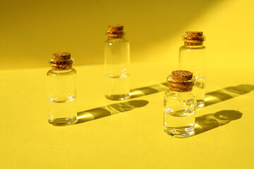 glass water bottles on illuminated yellow background under hard light. Minimalistic home decor, monochrome yellow. Reflection of water on the surface
