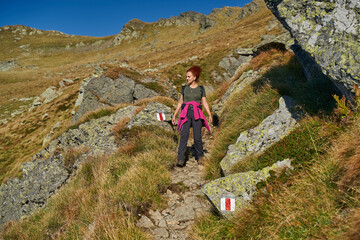 Fototapeta premium Woman hiker with backpack on a trail in the mountains