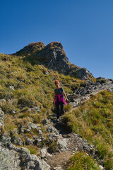 Woman hiker with backpack on a trail in the mountains