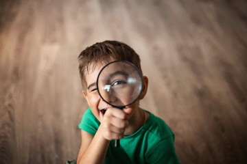 The boy looks through a magnifying glass. The child is holding a magnifying glass. Child's eye...