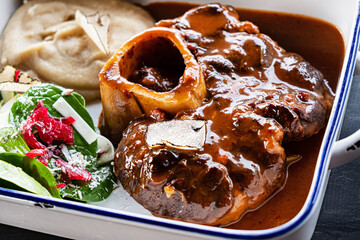 Close up of tasty roasted veal gremolata with tomato sauce and parsley in plate on table