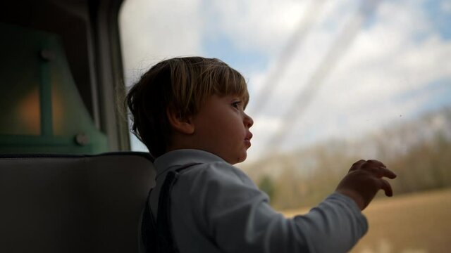 Child travelling by train, little boy looking out window looking at landscape passing by