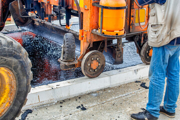 Melting asphalt with paver machine and placing gravel