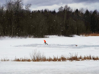 Solo training of a hockey player on a makeshift ice rink on a frozen lake. Healthy lifestyle, sports concept