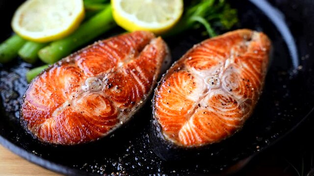 roasted salmon fillet steak with broccolini and lemon slice on iron skillet pan
