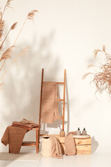 Natural waffle linen towels in earth tones on wood bench and towel ladder with bamboo toothbrushes,...
