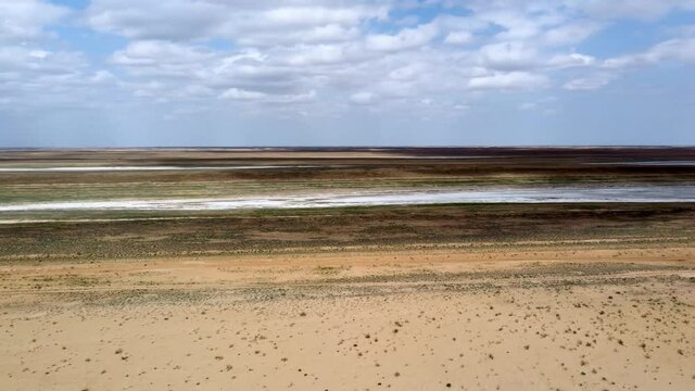 Panoramic view from the horizon to the drying salt lakes in the semi-desert. The local road goes along the ridges between the lakes