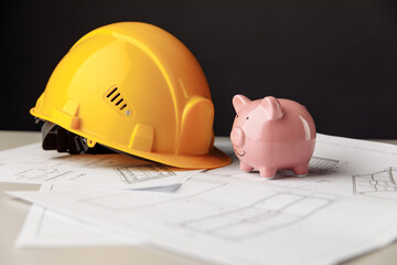 Construction safety helmet and piggy bank with blueprint