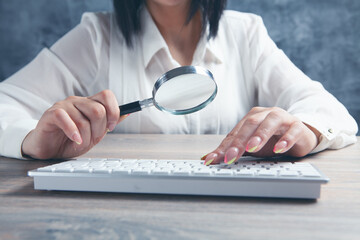 woman looking at the keyboard with a magnifying glass