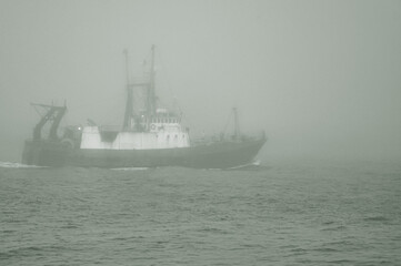 Fishing boat sailing through dense fog