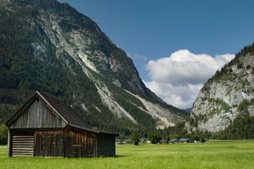Fototapeta na wymiar Houses between the shady rocky mountains in the Alps with cloudy sky, Upper Austria