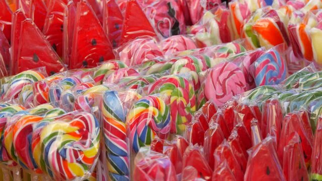 Row of beautiful multicolored lollipops on the counter of a candy shop store