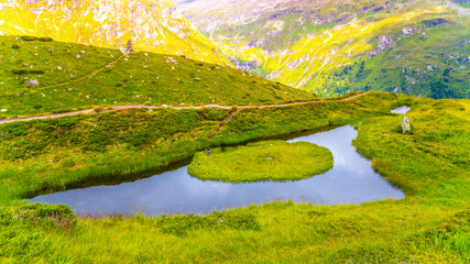 Eye of God, German: Auge Gottes. Small mountain lake with tiny green island in Venediger Group, Hohe Tauern National Park, Austrian Alps