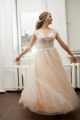Fototapeta premium Beautiful bride with a lush hairstyle in a pink dress indoors
