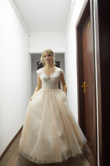 Fototapeta premium Beautiful bride with a lush hairstyle in a pink dress indoors