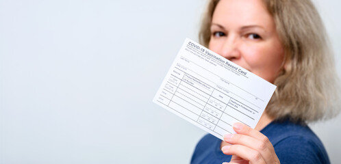 Young woman showing COVID-19 Vaccination Record Card. Vaccine theme for background. - obrazy, fototapety, plakaty