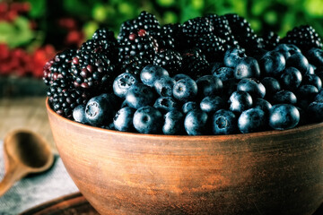 Ripe blueberry and blackberry berries in a deep ceramic bowl