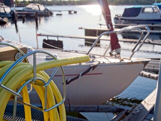 yellow water hose on boat dock. Sailboat in the background.
