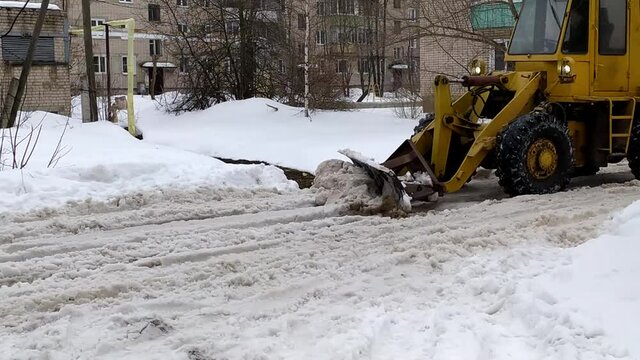 The tractor cleans the road from snow and mud. City improvement works. Road cleaning.