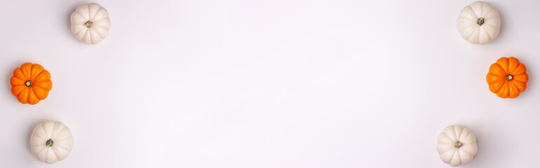 Flat lay banner of mini decorative pumpkin white, orange and yellow colors on bright background from above. Halloween and Thanksgiving greeting card holiday concept with copy space.