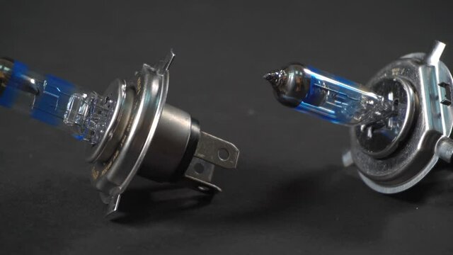 Halogen bulbs for car with silvery cap, panning on black background, type base H4, car component, closeup