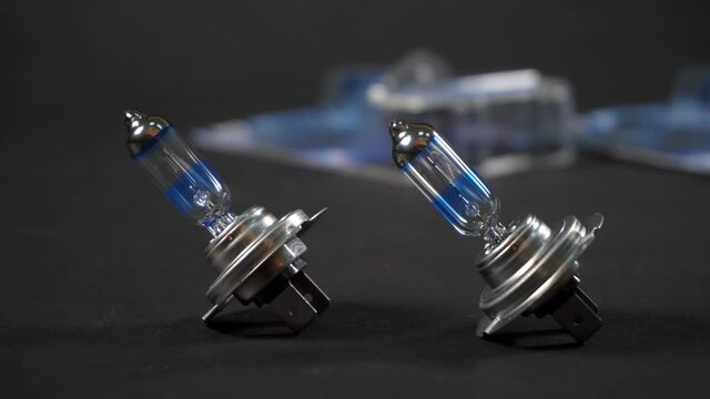 Halogen bulbs for car with silvery cap, panning on black background, H7, headlamp
