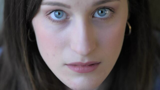 thoughts, worries . young woman looks up and stares serious at camera