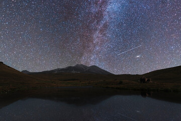 Beautiful night landscape, bright milky way galaxy over lake and mountains. Space, astronomical background. Summer night.