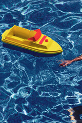 child's arm playing with toy boat in swimming pool