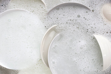 Washing dishes, Close up of utensils soaking in kitchen sink.