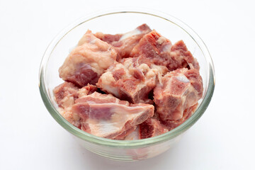 Raw pork ribs in glass bowl on white background.