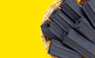 Non smoke wood charcoal in bamboo basket on yellow background.