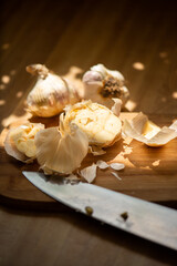 Fototapeta na wymiar Several garlic bulbs on cutting board with kitchen knife in foreground. 