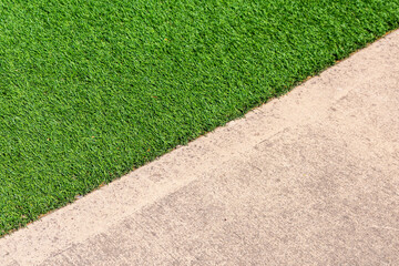Eco-friendly green artificial grass and concrete sidewalk. Close up