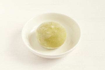 Green matcha tea Japanese dessert mochi on a small white bowls on a white wooden table. Closeup