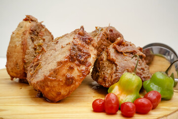 slice of pot cooked meat on wooden board with knife and cutlery.

